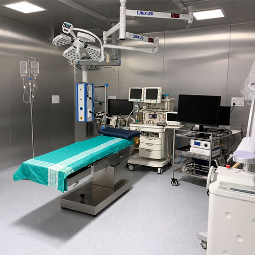 Modern operating room with surgical table, overhead lights, and medical equipment.